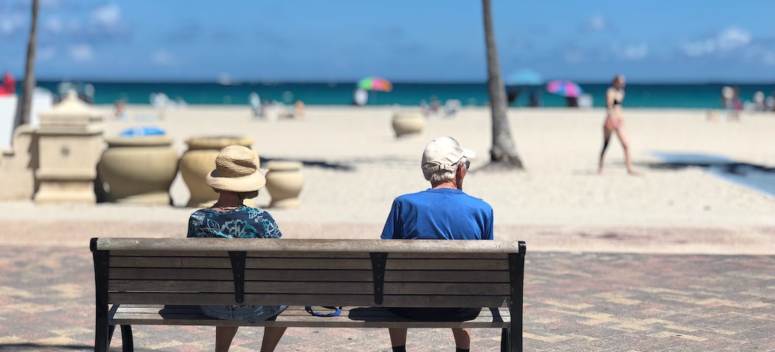 Elderly couple sitting on a bench next to a beach