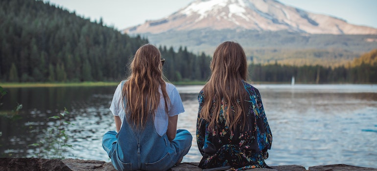 Two girls sitting next to a lake after moving from Illinois to Oregon