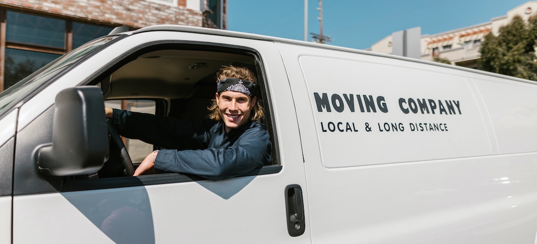 A man working for long distance moving companies Minnesota smiling in a van