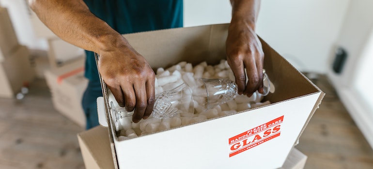 A mover packing glasses into a box