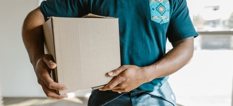 A mover holding a box while helping someone who is moving from New York to California