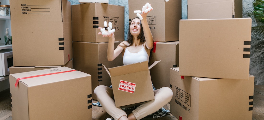 A woman playing with packing materials while sitting between boxes