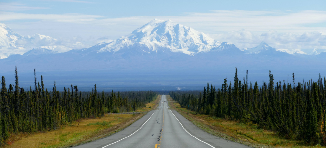 A road in Alaska going towards a mountain.