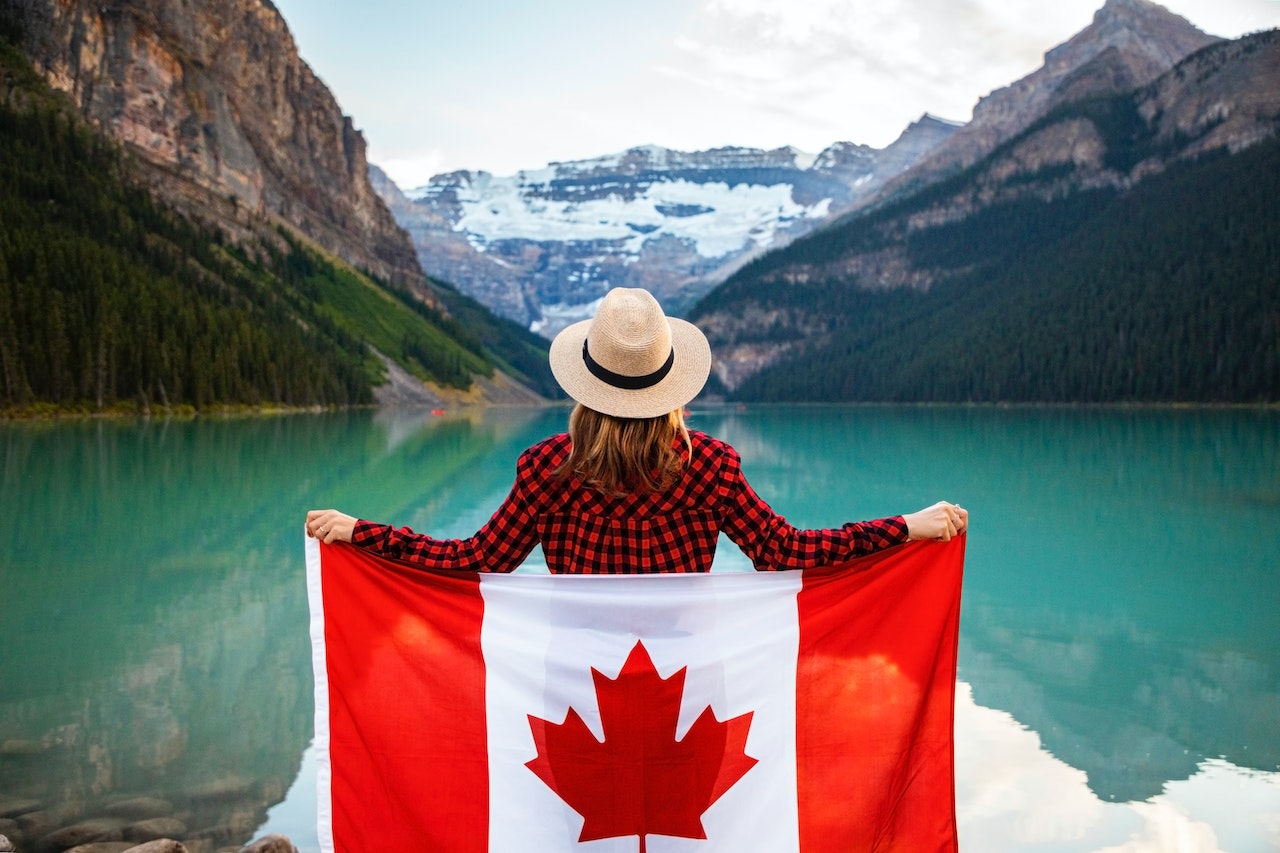 A woman holding a Canada flag next to a lake.
