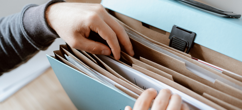 A person is going through the documents in a folder