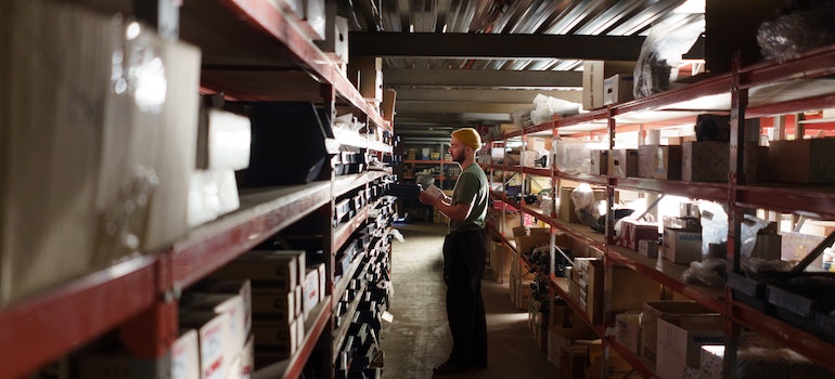 A man in a large storage facility trying to pick a right-sized unit, which is one of the ways for going green in your storage unit