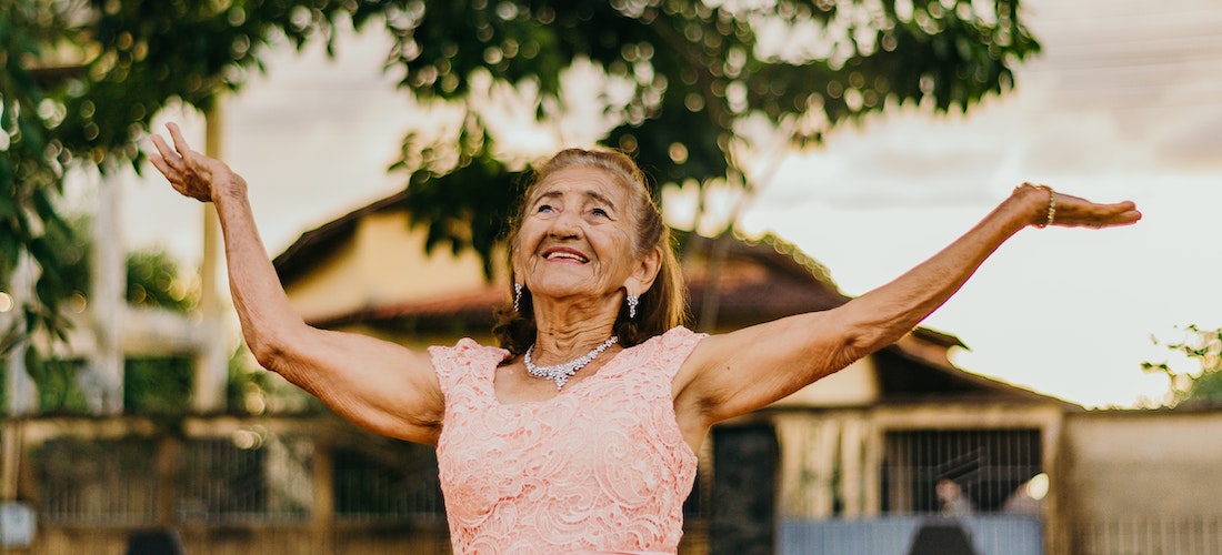 A happy elderly woman holding her hands in the air after having a successful move with cross country moving companies Enterprise