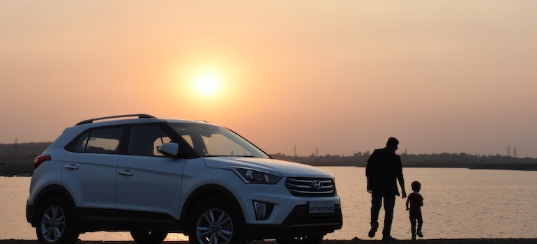 A dad and a sun next to their car during a sunset