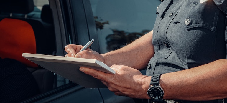 An officer writing a ticket to a person for not stopping at a weight station.