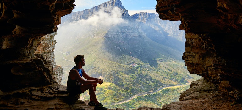 A person siting on the edge of a cave enjoying nature