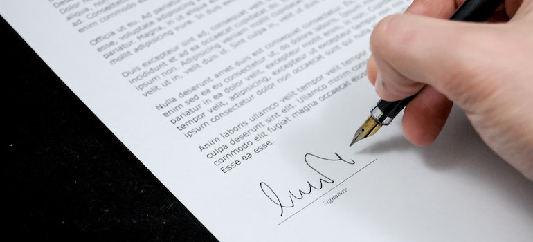 A person signing a document for car shipping preparation