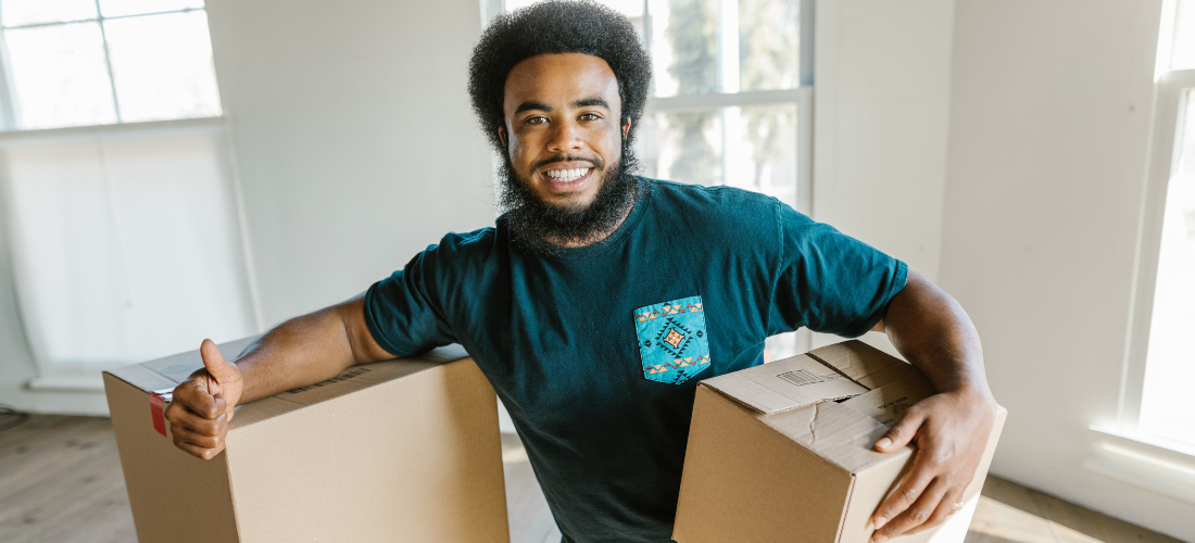 A man from cross country moving companies Alaska smiling while holding a box