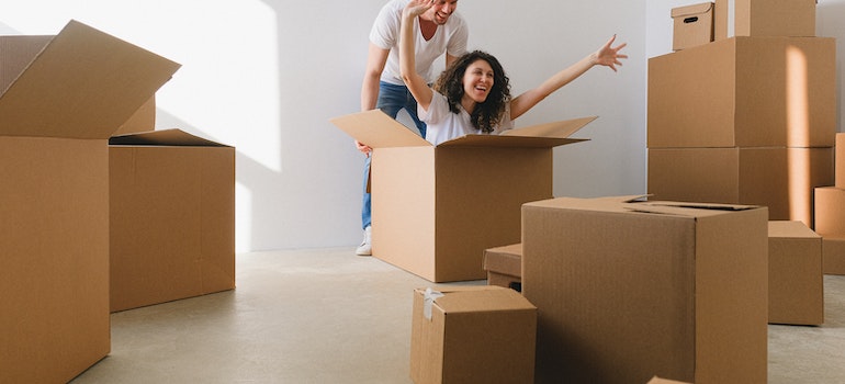 A couple having fun with moving boxes after reading useful tips for moving locally