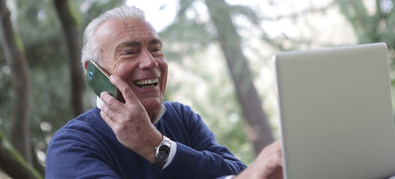 A man talking on his phone and looking for a moving company for senior moving online