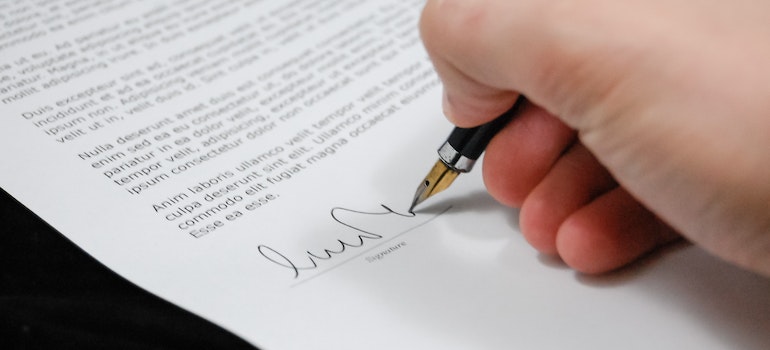 A person signing a document to purchase moving insurance