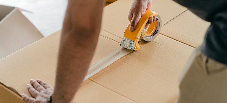 A man using a tape to seal a box