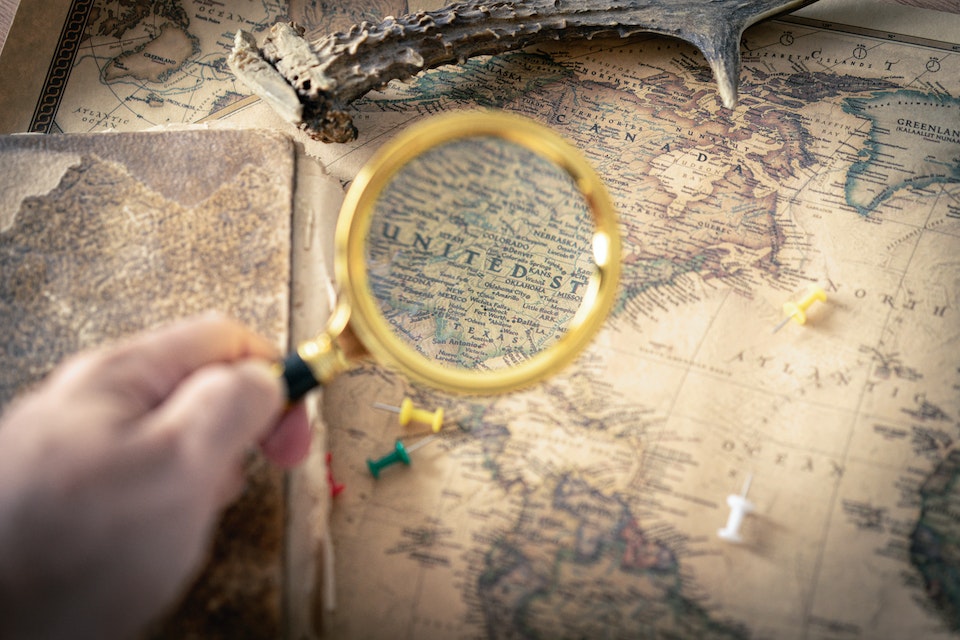 A person looking to the map of the USA through the magnifying glass