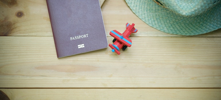 A passport on a table and a small toy plane next to it for moving to Australia from US