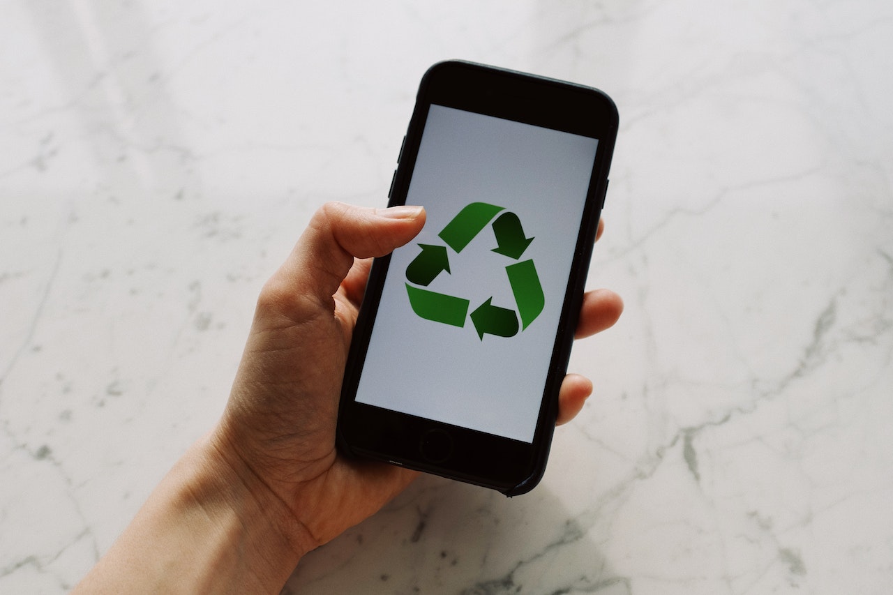 Person holding a smartphone with a recycling green sign for sustainability