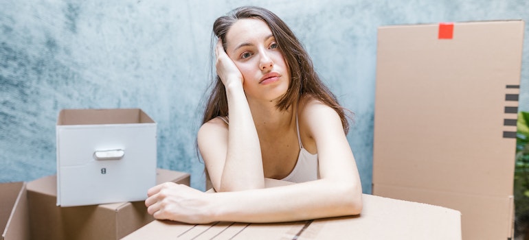 A woman next to a box, thinking about hidden moving costs