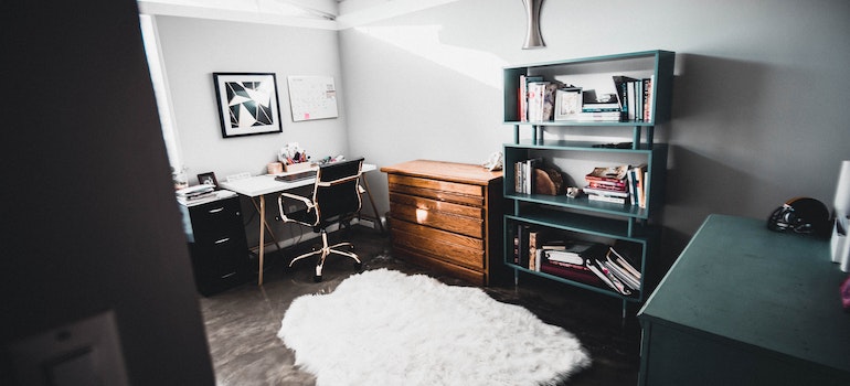 A room wit a desk, white rug and bookshelves