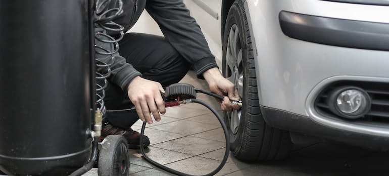 man checking tire pressure in car tires