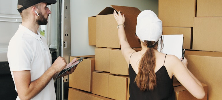 Man and woman looking at packed cardboard boxes in a van