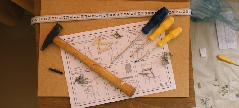Three screwdrivers, hammers and bolts on a professional furniture assembly manual that a person is using after a move