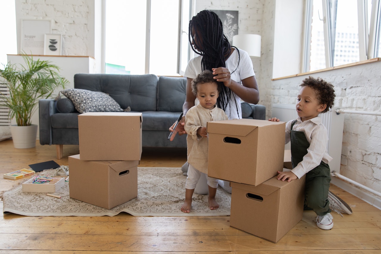 A woman packing stuff in cardboard boxes before moving long distance with kids