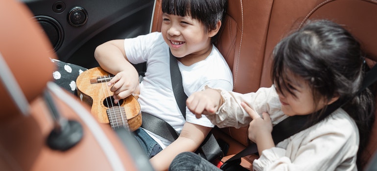 Kids in the back of the car playing with a ukelele