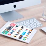 White iPad in front of a Mac computer with apps and tools