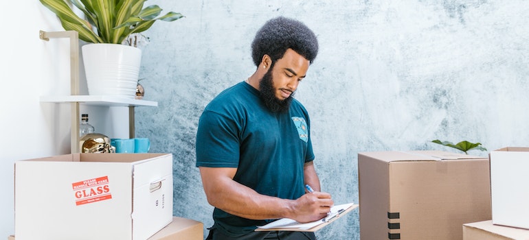 A mover counting boxes and writing in his white notepad