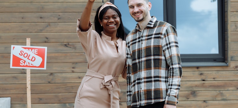 smiling couple holding a key to their new house