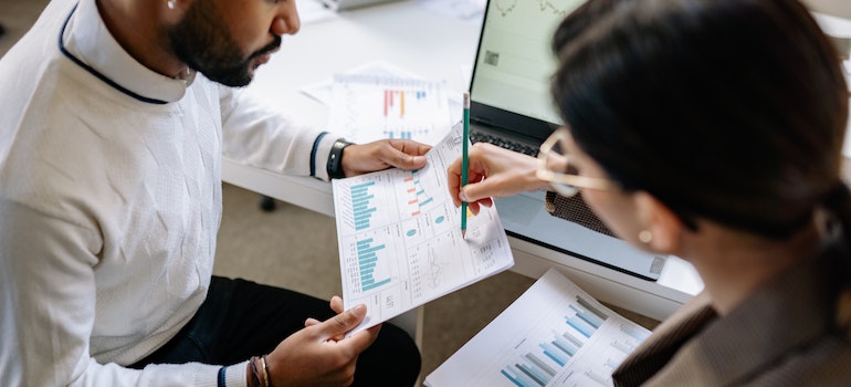 two people discussing charts printed on a piece of paper