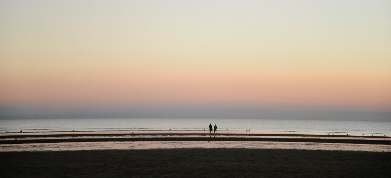 People walking on the beach during sunset in one of the places to retire in Massachusetts 