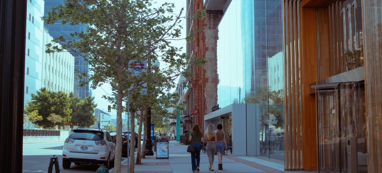 Three girls walking through downtown area near skyscrapers.