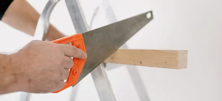A person using a saw - one of the most important tools for DIY home repairs after a move