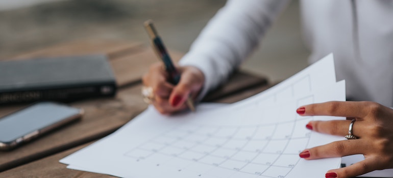 Woman writing and looking at a calendar to help her decide between moving locally vs. moving out of state