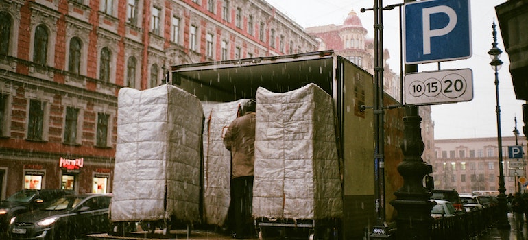 A moving truck in the rain being loaded with secured and covered items