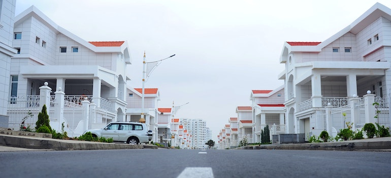Photo of a row of white houses wirth orange roofs with a white car parked in front of one