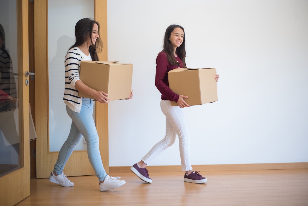Two girls carrying cardboard boxes