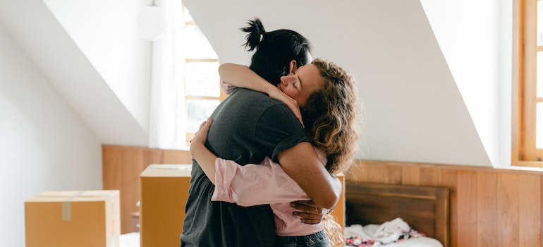 people hugging in a room full of moving boxes