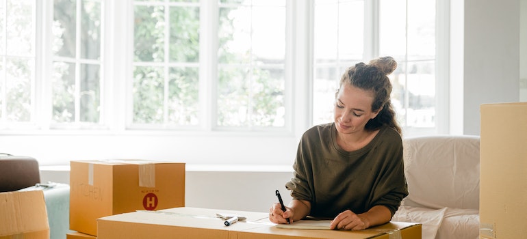 A woman labeling a moving box and thinking about the best time of year to schedule a local move in your city