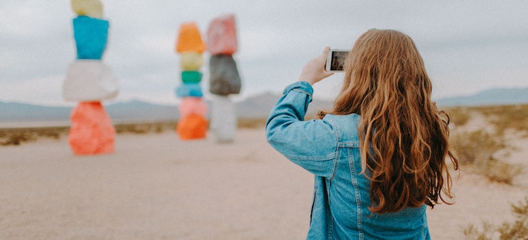 A woman taking a picture of colorful stacked rocks after moving from Washington to Nevada