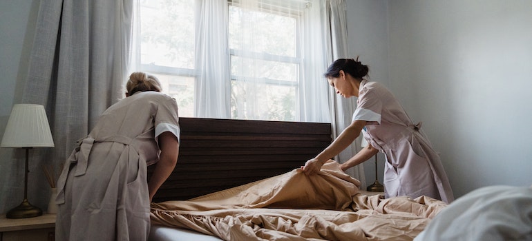 Two women in uniform making up the bed