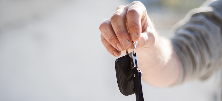 A man holding car keys before getting ready to transport specialty cars