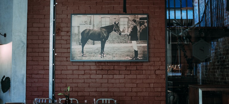A photo of a man with his horse on a brick wall
