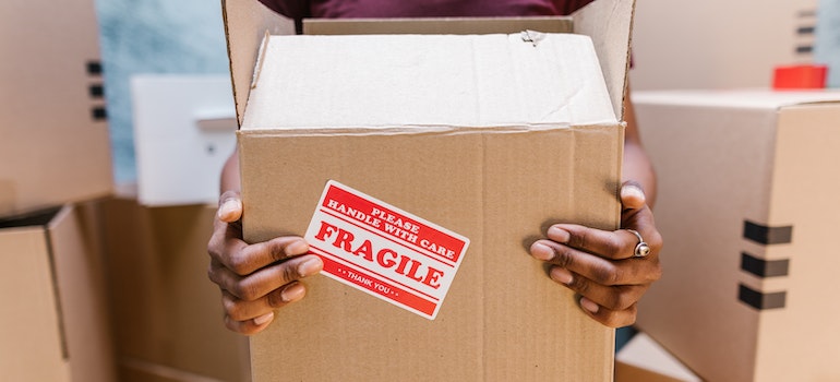 A woman holding a box with a fragile sticker on it
