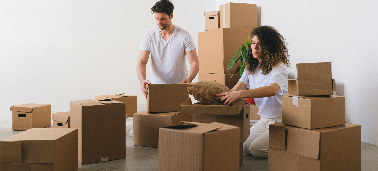 A curly woman and a man packing their things on their own because they didn't want to use a full-service long distance moving company
