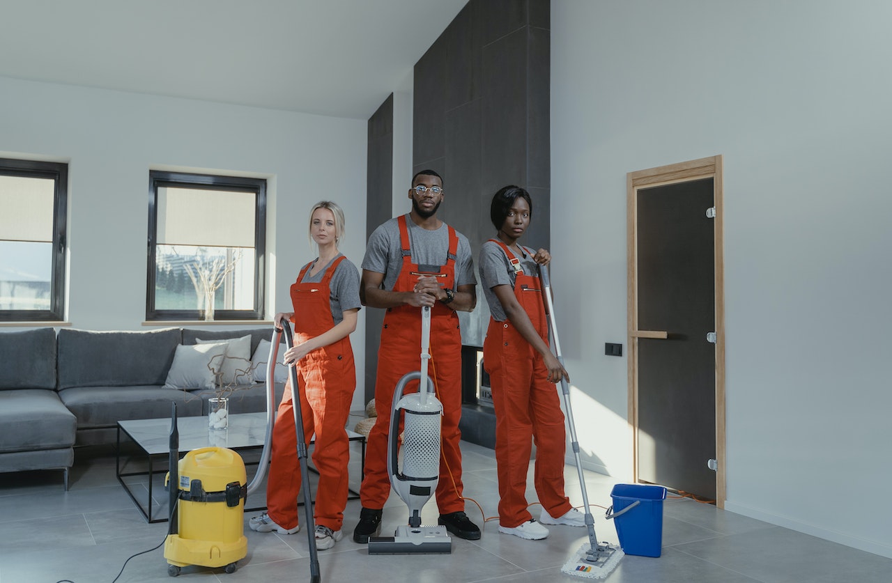 Three members of a professional cleaning crew with cleaning supplies